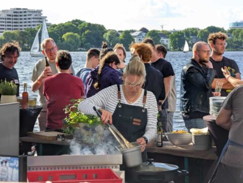 Grillparty am See mit Segelbooten im Hintergrund