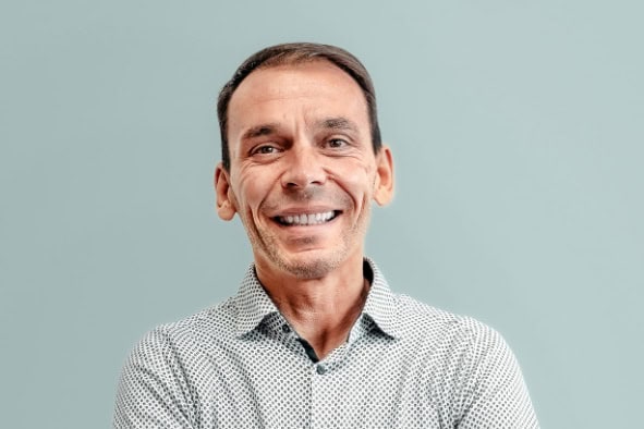 Christian Fink, professioneller Geschäftsmann, lächelt vor hellem Hintergrund.